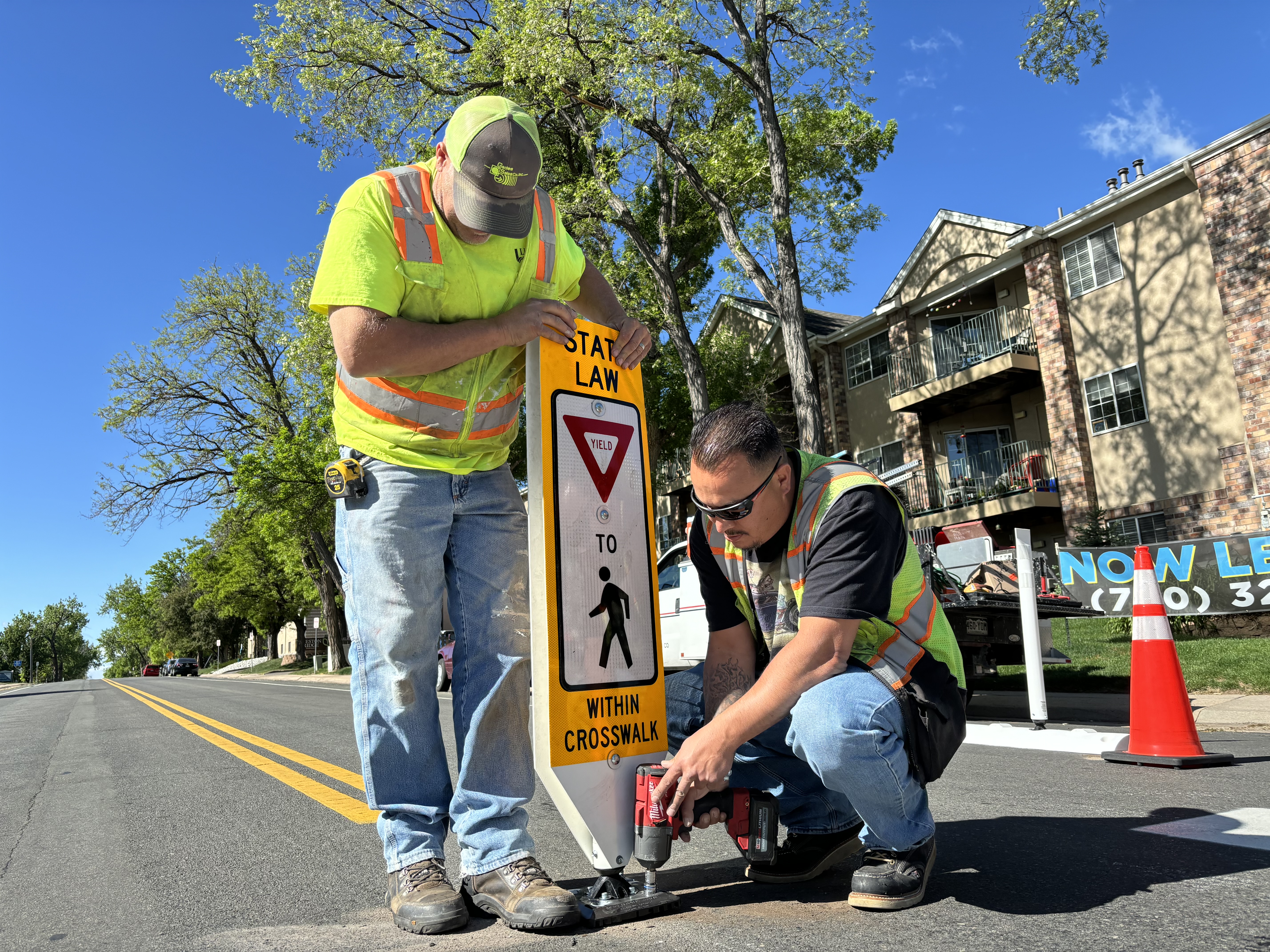 Two men installing an in-road pedestrian sign.
