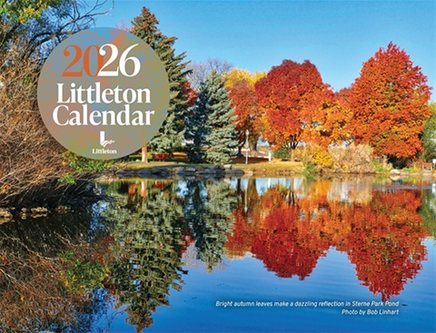  Colorful autumn trees reflect in a calm pond under a clear blue sky; 2026 Littleton Calendar cover. 